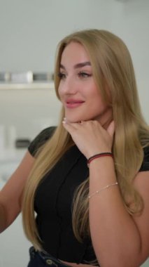 Sarışın, yeşil gözlü, gülümseyen ve kameraya bakan güzel yüzlü kız.