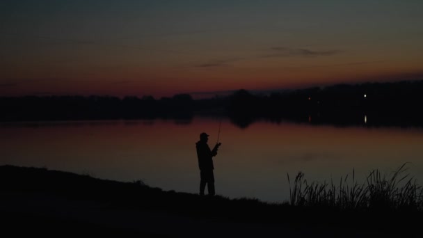 夕日の背景に川で釣り竿を投げてシルエット漁師 川で釣り中に美しい夕日 スポーツ趣味釣り — ストック動画