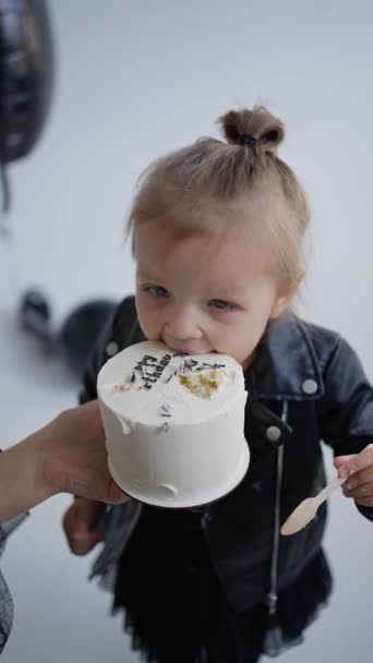 子供のクローズアップは クリームでケーキの大きな部分を食べています 小さな女の子が彼女の口を開き 彼女の歯でケーキを噛む ポートレイト オーヴェイジング バースデー — ストック動画