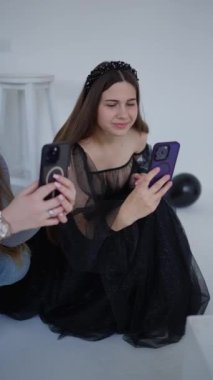 Güzel, şık bir genç kız stüdyoda eğleniyor ve cep telefonuyla fotoğraf çekiyor. Eğlence ve kutlama konsepti