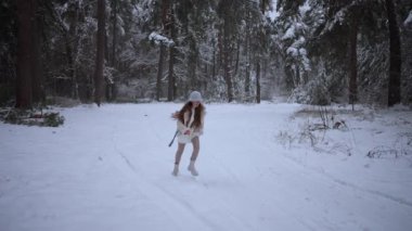 Bir kız kışın karlı bir ormanda yürür. Şapkalı ve kalın elbiseli mutlu bir ergen kız arkadaşıyla buluşmak için koşar.