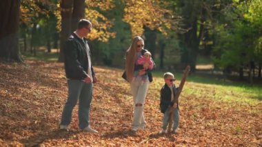 Aile, sonbaharda parkta küçük oğlu ve kızıyla oynuyor.