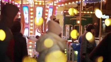 Küçük mutlu çocuklar, kış mevsiminde lunaparkta eğlenceli bir gezinti yaparak atlı karıncaya biniyorlar. Noel kutlamaları