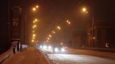 Gece sokağı. Arabalar karlı yolda ilerler. Geceleri kar fırtınası sırasında arabalar geçer.