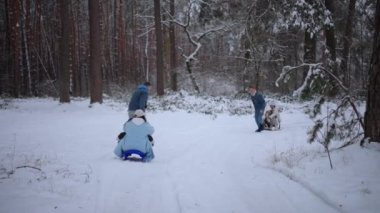 Babam kış ormanlarında koşuyor ve kızak çekiyor, mutlu bir aile hafta sonu.