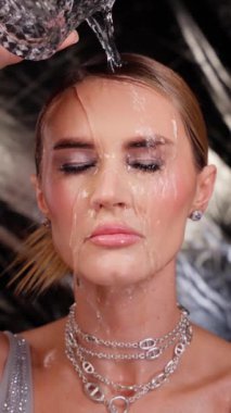 Güzel genç bir kadının yüzüne su sıçrıyor.