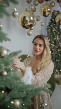 Noel süslemelerinin arka planında altın sarısı parlak gece elbisesi içinde seksi, şık, güzel bir kadın..