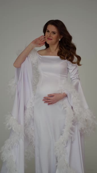 Femme Enceinte Rayonnante Dans Une Robe Blanche Chic Ornée Plumes — Video
