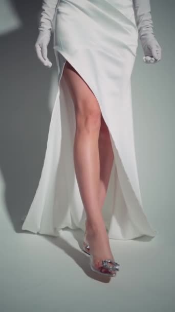 穿着白色长袍的女人端庄的姿态 她的腿在狭缝中保持着端庄的姿势 穿着华丽华丽的鞋子 — 图库视频影像