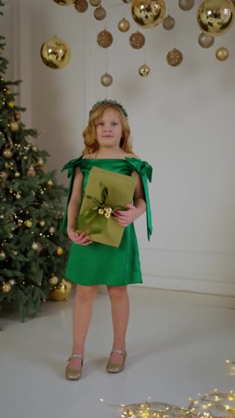 Criança Alegre Vestido Verde Mantém Presente Natal Cercado Por Decorações — Vídeo de Stock