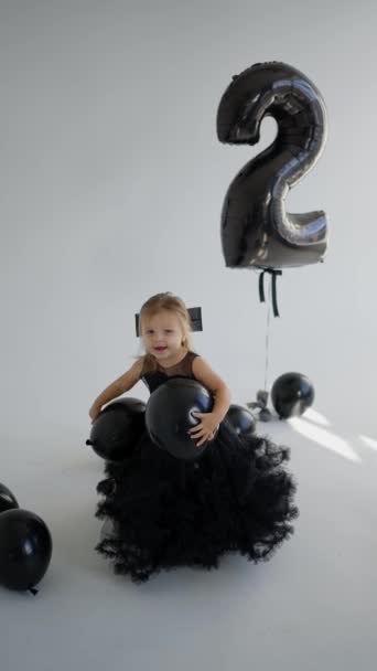 黒で2歳の誕生日を祝う 風船が付いている黒いドレスの子供 — ストック動画