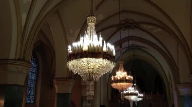İki büyük kristal avize, süslü kilise salonunun üzerine sıcak bir ışık saçıyor..