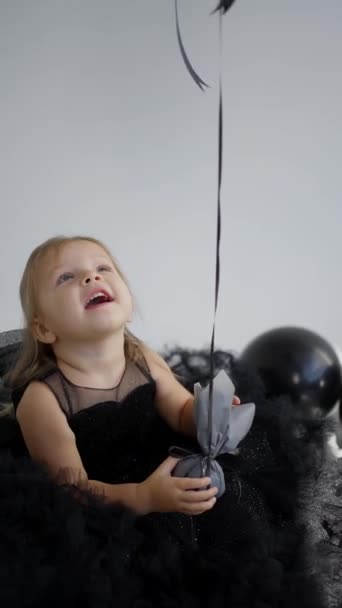Маленька Дівчинка Грає Гелевим Ячем Вечірній Чорній Сукні Святкуючи День — стокове відео