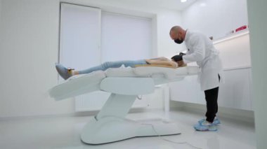 Güzellik salonundaki müşterinin yüzüne gençleştirici botoks doldurucu şırınga enjekte eden konsantre olmuş bir güzellik uzmanı. Coronavirus maskeli bir adam genç bir kadın için yaşlanma karşıtı işlem yapıyor.