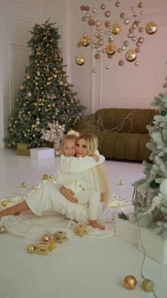 若い母親がアパートで娘と遊んでいる 休暇で一緒に楽しんでいる家族を愛する 背景には装飾が施されたクリスマスツリーが見えます — ストック動画