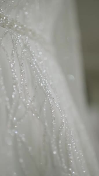 Détails d'une robe de mariée blanche décorée de perles.