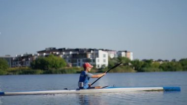 Bir adam gölün karşısına geçer, zarif bir şekilde kürek çeker..