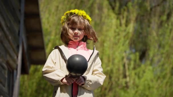 Klein Kind Paardenbloem Krans Houdt Zwarte Ballon Buiten — Stockvideo