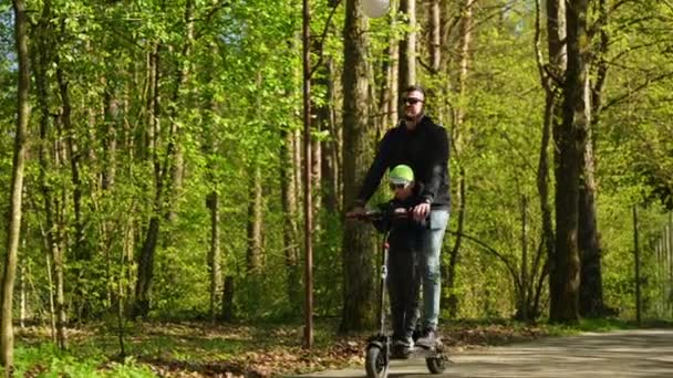 Ein Mann Und Sein Sohn Fahren Mit Einem Motorroller Park — Stockvideo