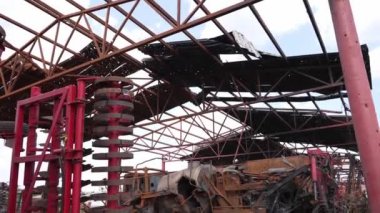 Çatı delikli hangar yapıları altında bozulmuş arabalar var..