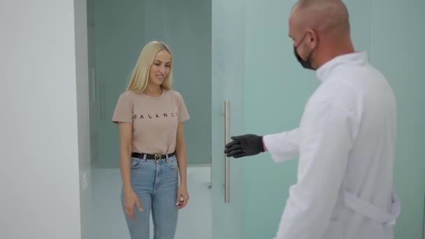Kobieta Lekkich Ubraniach Wchodzi Biura Jest Spotykany Przez Lekarza Białym — Wideo stockowe