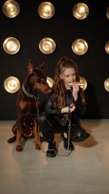 Mızıka çalan küçük bir müzisyen, Sadık Doberman yakınlardaki gösteriyi izlerken.