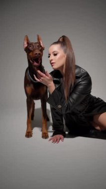 Yerde oturan genç kadın, ilgiyle tepki veren Doberman 'ın dikkatini çekiyor..