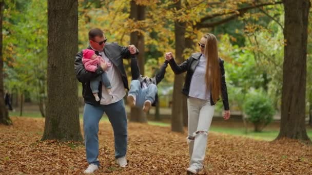 가을의 기쁨은 소년으로 미소와 잎으로 공원에서 산책하는 부모와 — 비디오