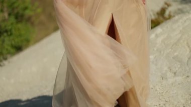 Fısıldayan ağaçların arasında, narin bej elbiseli düşünceli bir kadın, narin yürüyüşündeki dinginliğin özünü temsil ediyor..