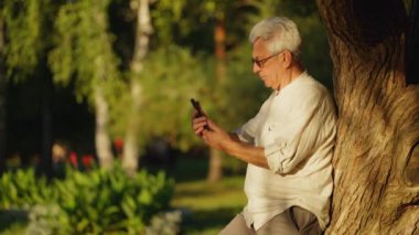 Serene Afternoon Tech Bağlantısı. Huzurlu göl kenarında akıllı telefon kullanan kıdemli bir adam.