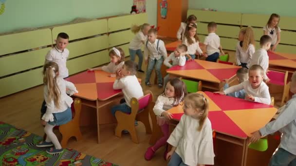 Различные Детские Взаимодействия Происходят Ярком Красочном Классе Деревянными Столами — стоковое видео