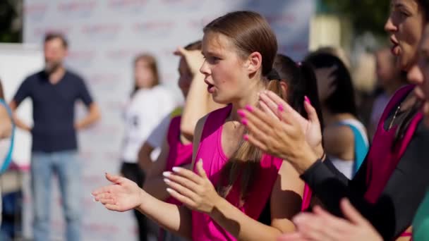 团体在户外活动中欢呼 关注穿着粉色衣服的年轻女子 — 图库视频影像