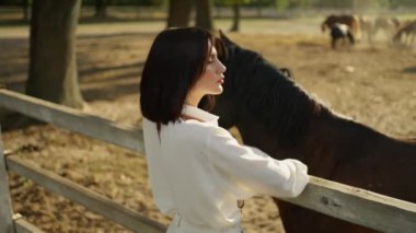 Beyaz atlı genç bir kadın çiftlikte atla bağ kuruyor..