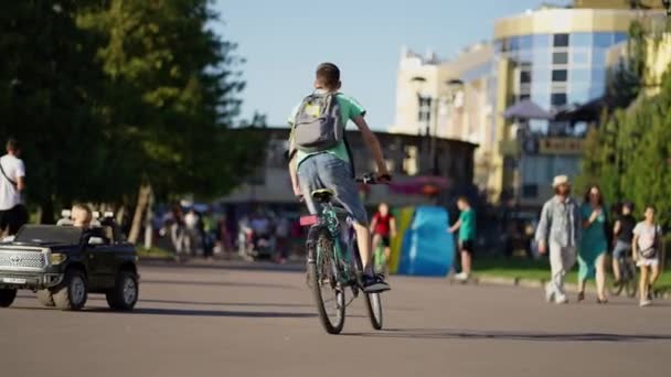 Подростковый Велосипед Парке Людьми Игрушечными Машинами Вокруг — стоковое видео