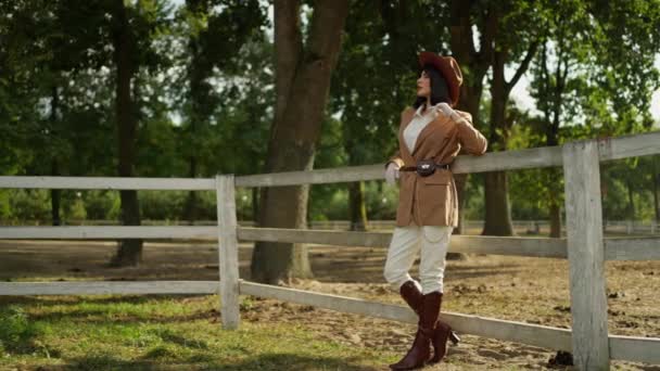 穿着马术的时髦女人靠在牧场篱笆上 — 图库视频影像