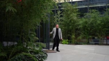 Kasıtlı bir yürüyüşle, bir işadamı ofisinden ayrılıp bambu ve eğreltiotu vahasına giriyor..