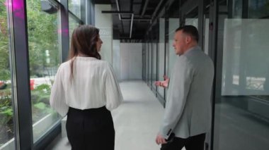 İki şirket çalışanı koridorda yeşillikle övünen stratejiyi düşünmek için durdular..