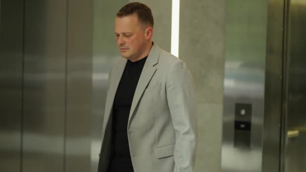 Muž Obleku Kráčí Výtahovou Halou Ztělesňuje Osamělost Uprostřed Firemního Shonu — Stock video