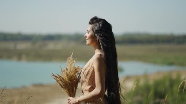 Backdrop Serene Lake Woman Flowing Beige Dress Holds Sheaf Wheat — Stock Video