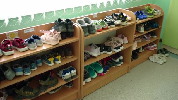 遊び場の靴の棚はさまざまなサイズの多彩な靴そしてスニーカーで満ちています — ストック動画