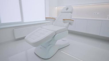 Kliniğin içinde ahşap elementler olan beyaz kozmetoloji koltuğu, insan yok..