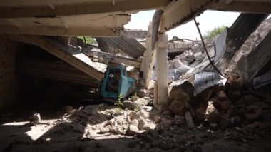 Çökmüş hangar yapıları sıkışmış yeşil araba, her yerde yıkım izleri var..