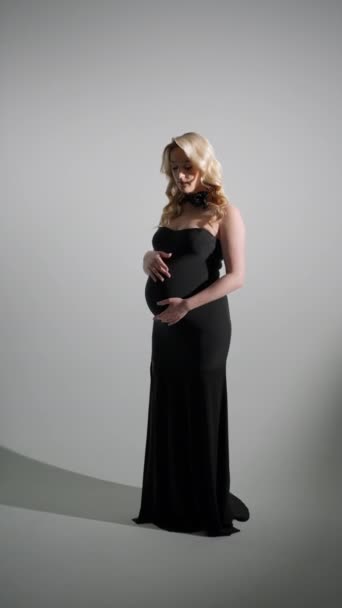 穿着黑色衣服的年轻孕妇在黑暗的房间里爱抚着她的腹部 未来母亲的概念 — 图库视频影像