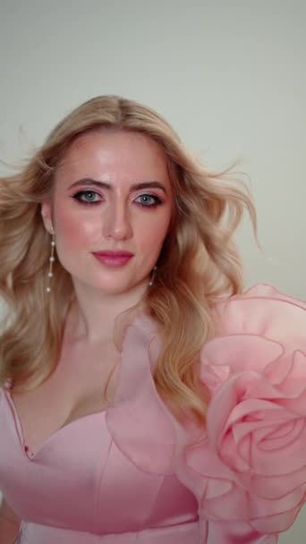 妆容和珍珠耳环都是金发碧眼的女人 配着粉色的衣服 手里拿着巨大的玫瑰 — 图库视频影像