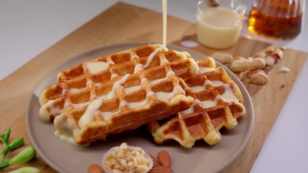 比利时华夫饼 上面涂满了丰富的奶油白色巧克力酱 用坚果和蜂蜜放在盘子里 — 图库视频影像