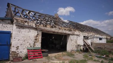 Kısmen yıkılmış çatılı, duvarları ve toprağı soyan çiftlik evi kalıntıları..