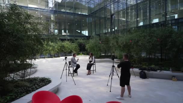 Przestronnym Atrium Szklanymi Ścianami Dwoje Profesjonalistów Prowadzi Rozmowy Otoczone Kamerami — Wideo stockowe
