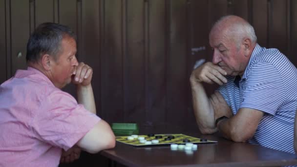 Dois Homens Seniores Envolvidos Jogo Damas Parque Ponderando Seus Próximos — Vídeo de Stock