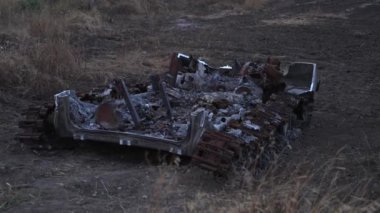 Harap olmuş toprakların arka planına çarpık metal ve yanmış parçalarla tahrip edilmiş tankın karanlık görüntüsü..
