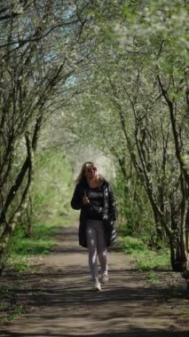 Mutlu bir kadın baharda açan büyük ağaçların altında yürüyor..